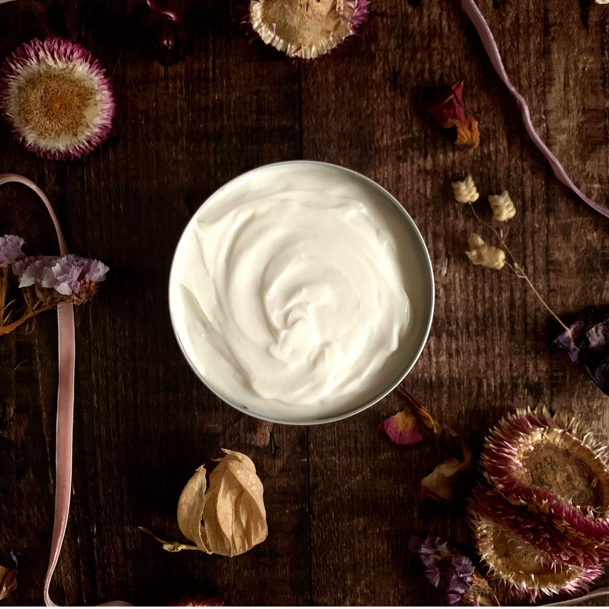 Hedgerow and Moor Body cream in a jar on a wooden surface with dried flowers