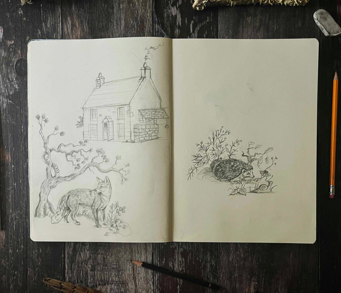 An open sketchbook showing pencil drawings of a traditional farmhouse and woodland animals