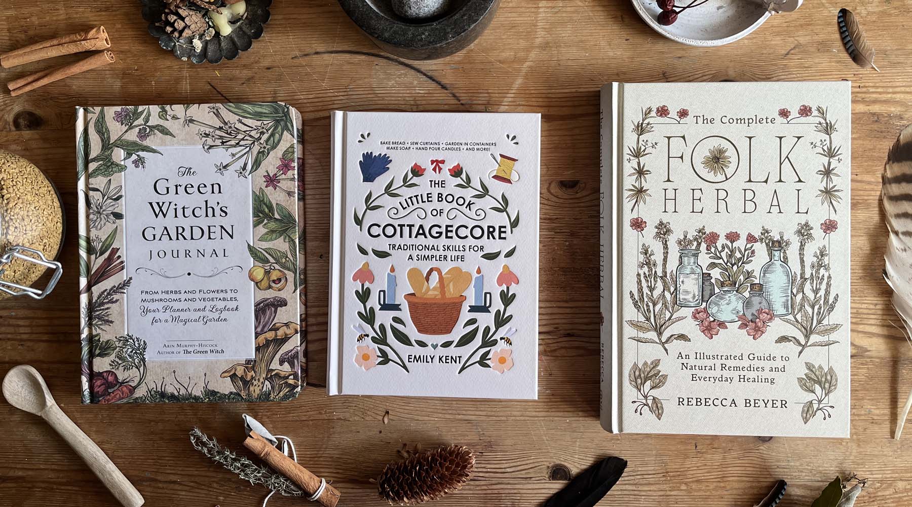 A curated stack of folk herbalism and plant-lore books styled with dried herbs and natural textures for the Hedgerow & Moor books collection