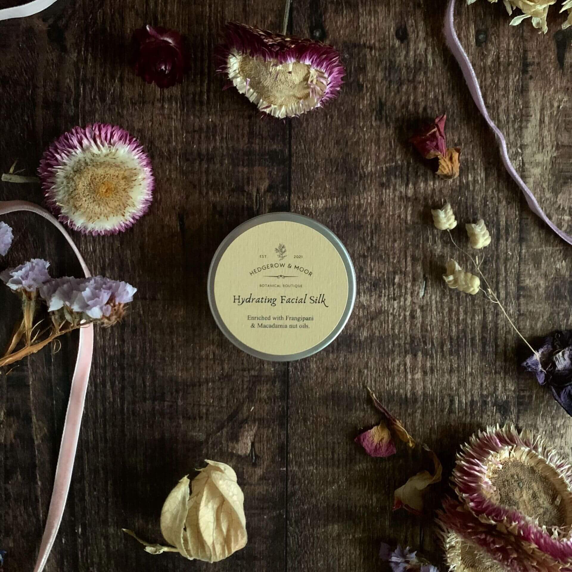 Luxury natural face cream in an aluminium jar on a rustic wooden surface, Hydrating Facial Silk by Hedgerow & Moor — vegan, plastic-free skincare made in Cornwall.