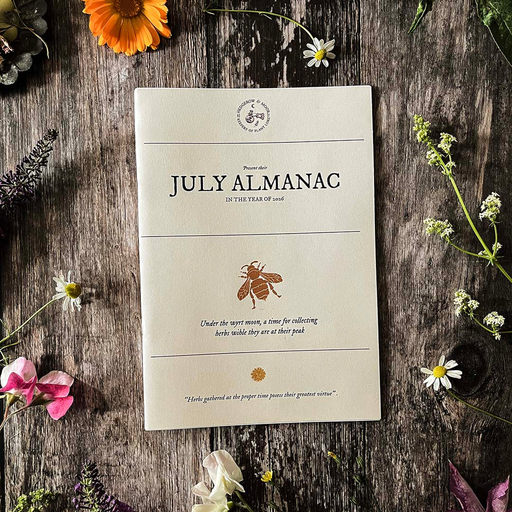 Hedegrow and moor July Almanac on a wooden surface with flowers