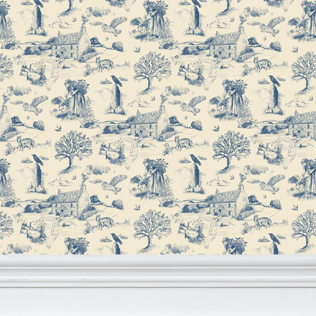 Blue and cream Hedgerow and Moor  toile pattern wallpaper with a repeating French countryside scene featuring trees, houses, birds, and animals, shown above a white baseboard.