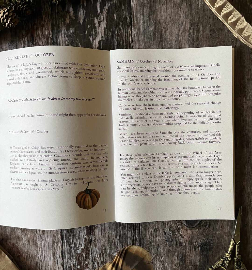 An open hedgerow and moor october almanac zine spread spread showing printed text pages, photographed on a dark textured fabric background with a small orange pumpkin prop near the bottom center.