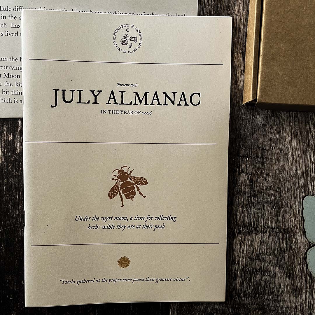 Hedgerow and Moor July Almanac on a wooden surface with a bee illustration