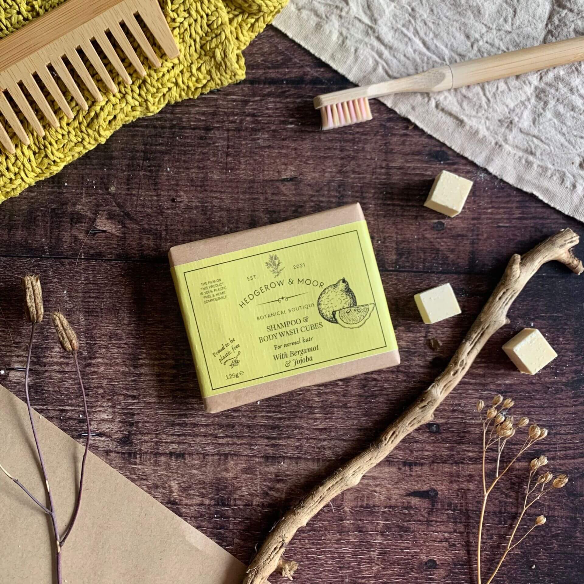 Plastic-free shampoo cubes for normal hair by Hedgerow & Moor — pack of cubes with a few loose pieces beside it on a wooden surface. Vegan, sulphate-free, handmade in Cornwall.