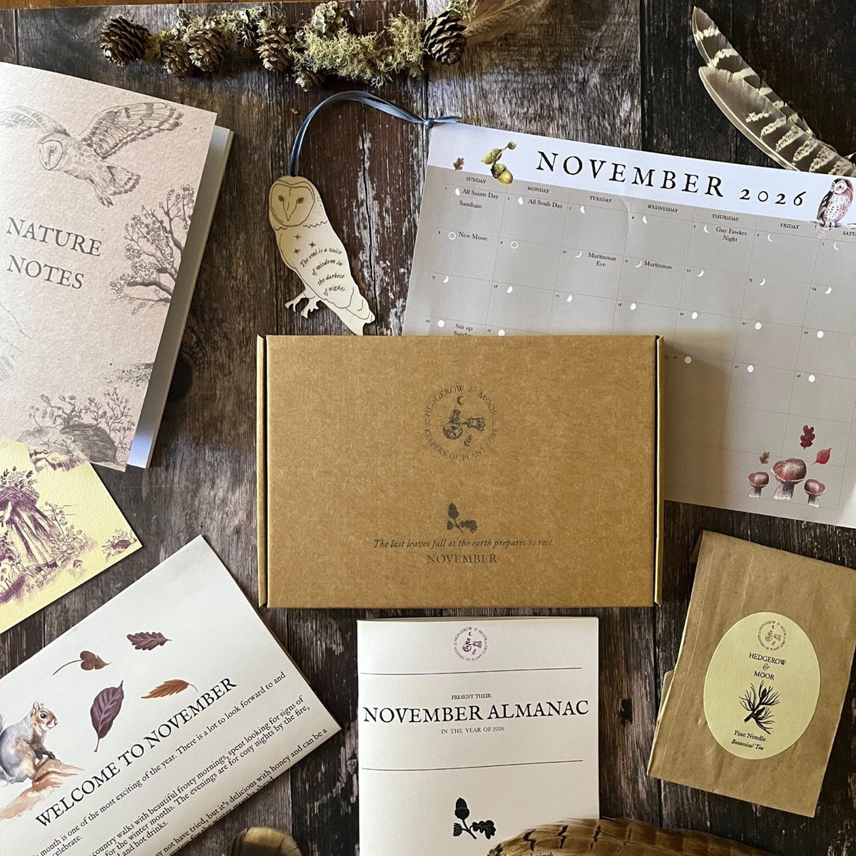 November 2026 Hedgerow & Moor Almanac box arranged with zine, calendar, Pine Needle Tea, wooden owl and Nature Notes notebook.