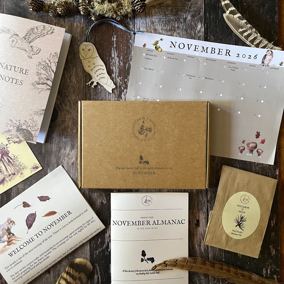 November 2026 Almanac collection showing the wooden owl beside the illustrated moon-phase calendar and seasonal zine.