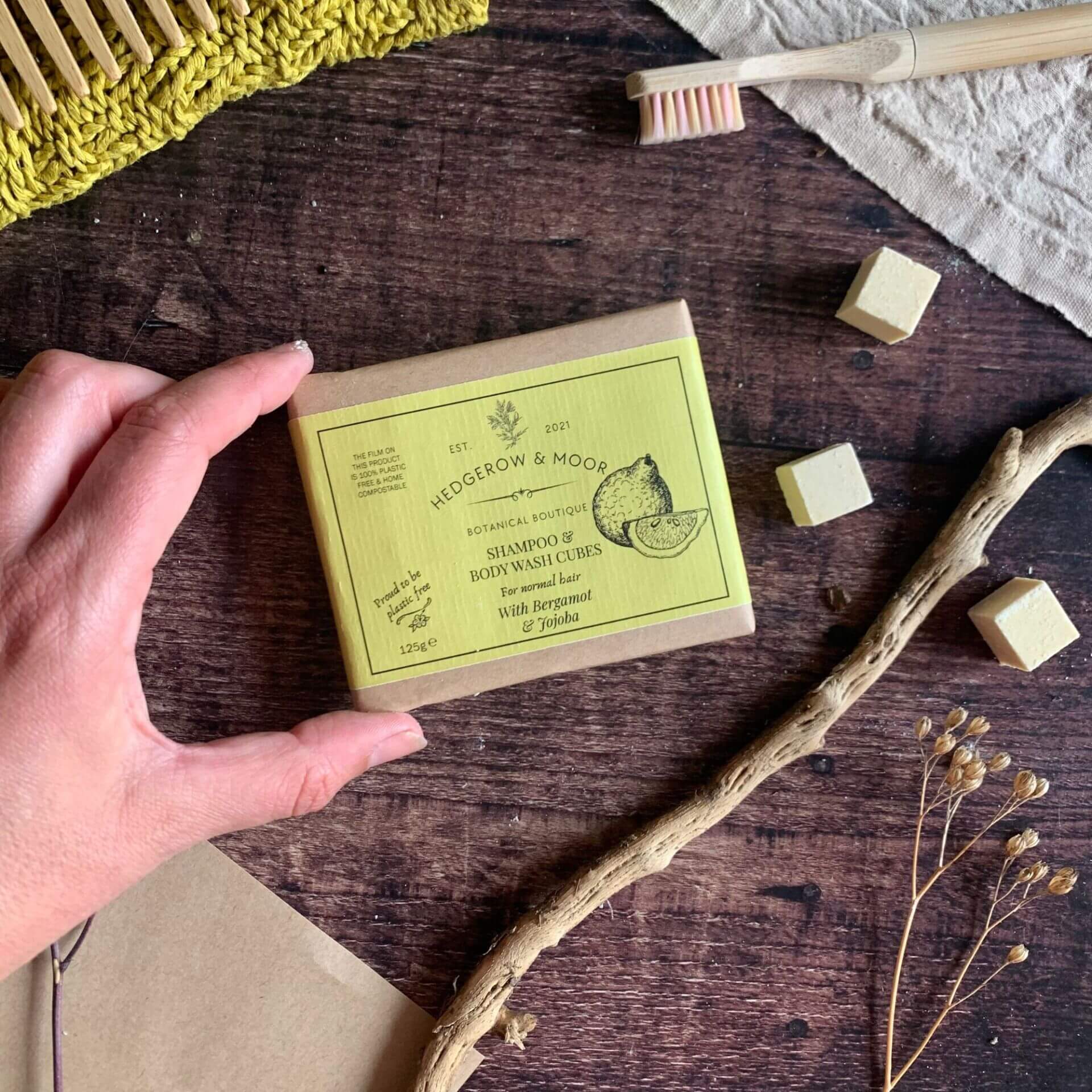 Close-up of Hedgerow & Moor shampoo cubes showing smooth texture and natural finish beside eco-friendly packaging on a rustic wooden background.