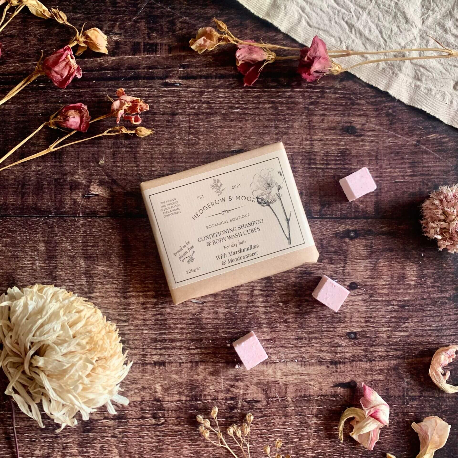 Plastic-free shampoo and body wash cubes in an open aluminium tin on a wooden surface — vegan, sulphate-free hair and body care by Hedgerow & Moor, handmade in Cornwall.

Why it works: